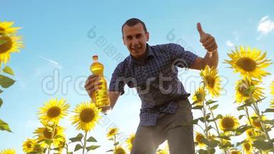 男人手里拿着一个塑料生活方式瓶<strong>葵花油</strong>站在田野里。 慢速视频
